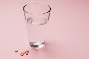 Glass of water next to a few tablets