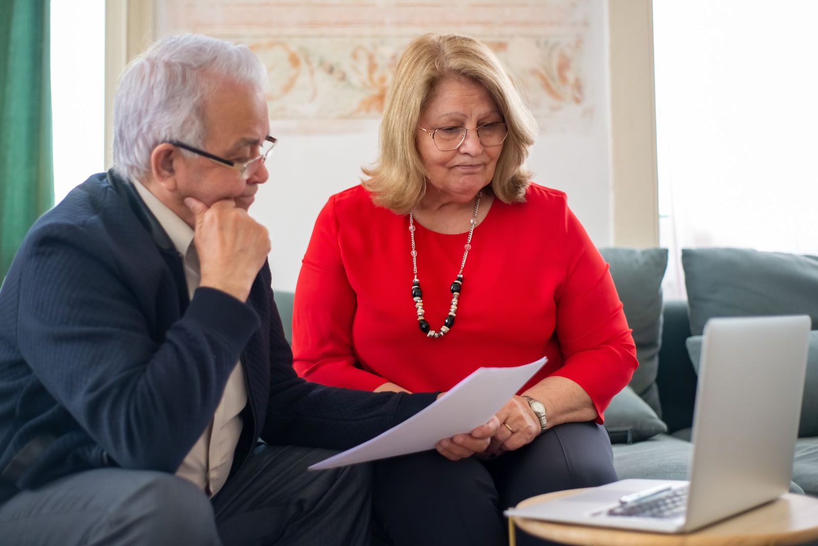 Senior couple reading through paperwork together at home