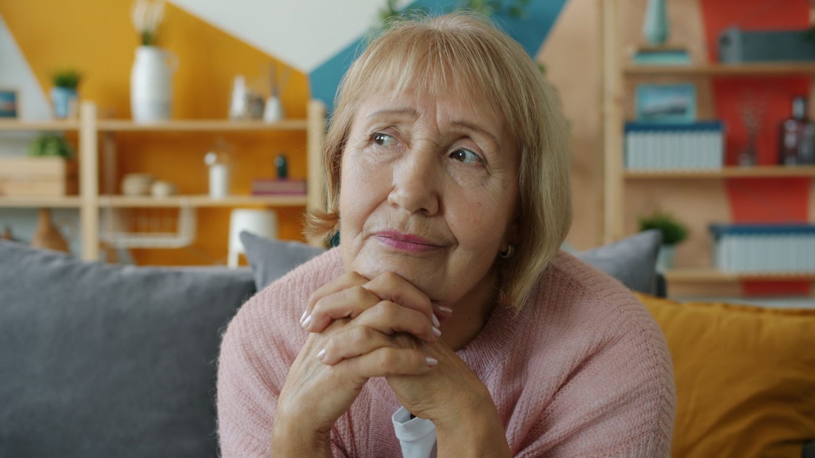 Older woman sitting on a sofa, looking thoughtful